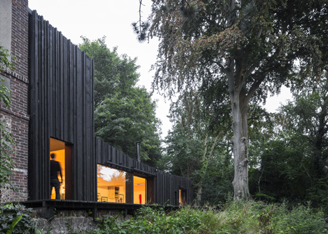 Blackened timber house extension with textured walls by Marchi Architectes