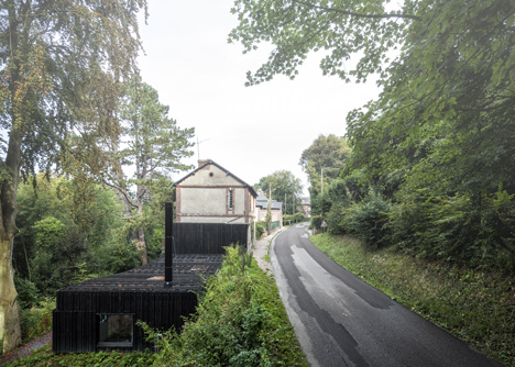 Blackened timber house extension with textured walls by Marchi Architectes