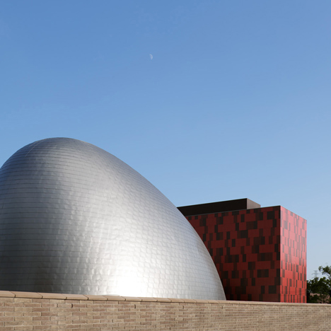 Blob-shaped silver building contrasts with a red tower at Japanese music college