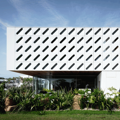 Diagonal slits pierce white shutters wrapping Casa Ventura by Arquitetura Nacional