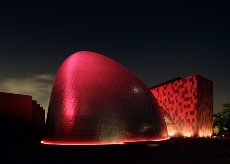 Blob-shaped silver building contrasts with a red tower at Japanese music college