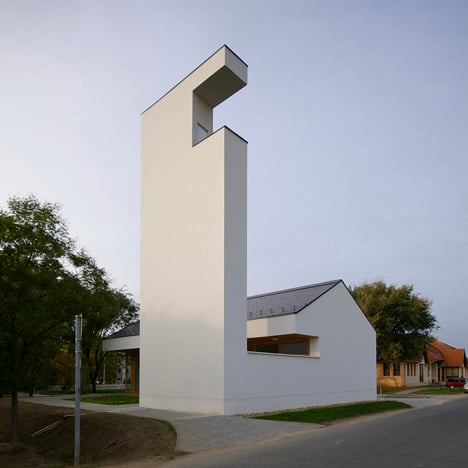 Church congregation hall by SAGRA Architects features a towering white bell tower