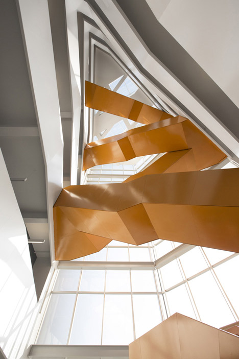 Grand orange staircase ascends through college by Saucier + Perrotte