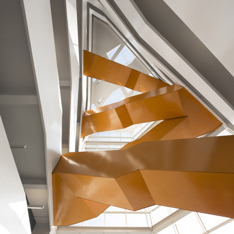 Grand orange staircase ascends through college by Saucier + Perrotte