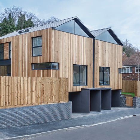 Twin wooden houses by Adam Knibb Architects are raised up above street level