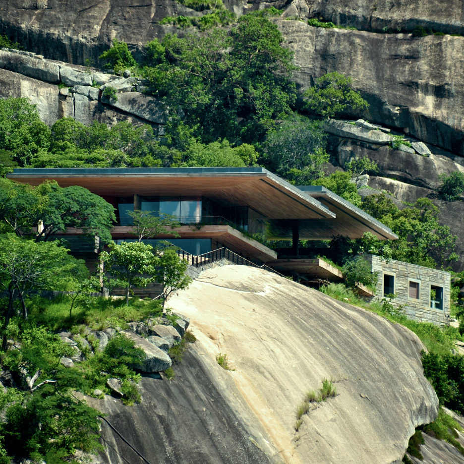 Timber and granite residence by Studio Seilern stands on a rocky ledge above an African dam