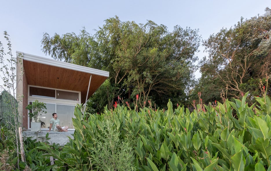 House 50 50 by Celula Urbana sits next to a river in Argentina