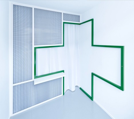 Green cross divides workspace from waiting room in denture clinic by Adam Wiercinski