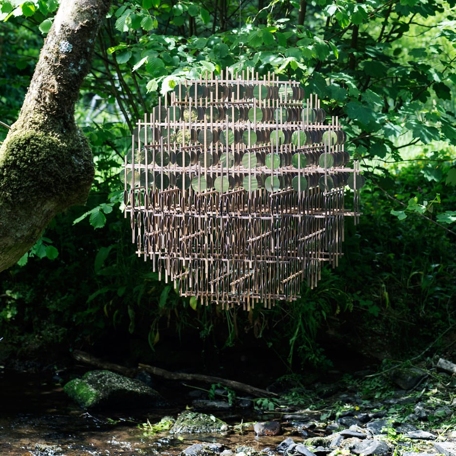 Giles Miller's Penny-Half Sphere sculpture is a "double-sided portal" hanging above a stream