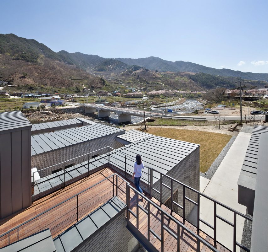 Rooftop bridge connects riverside house and roadside cafe in a South Korean valley