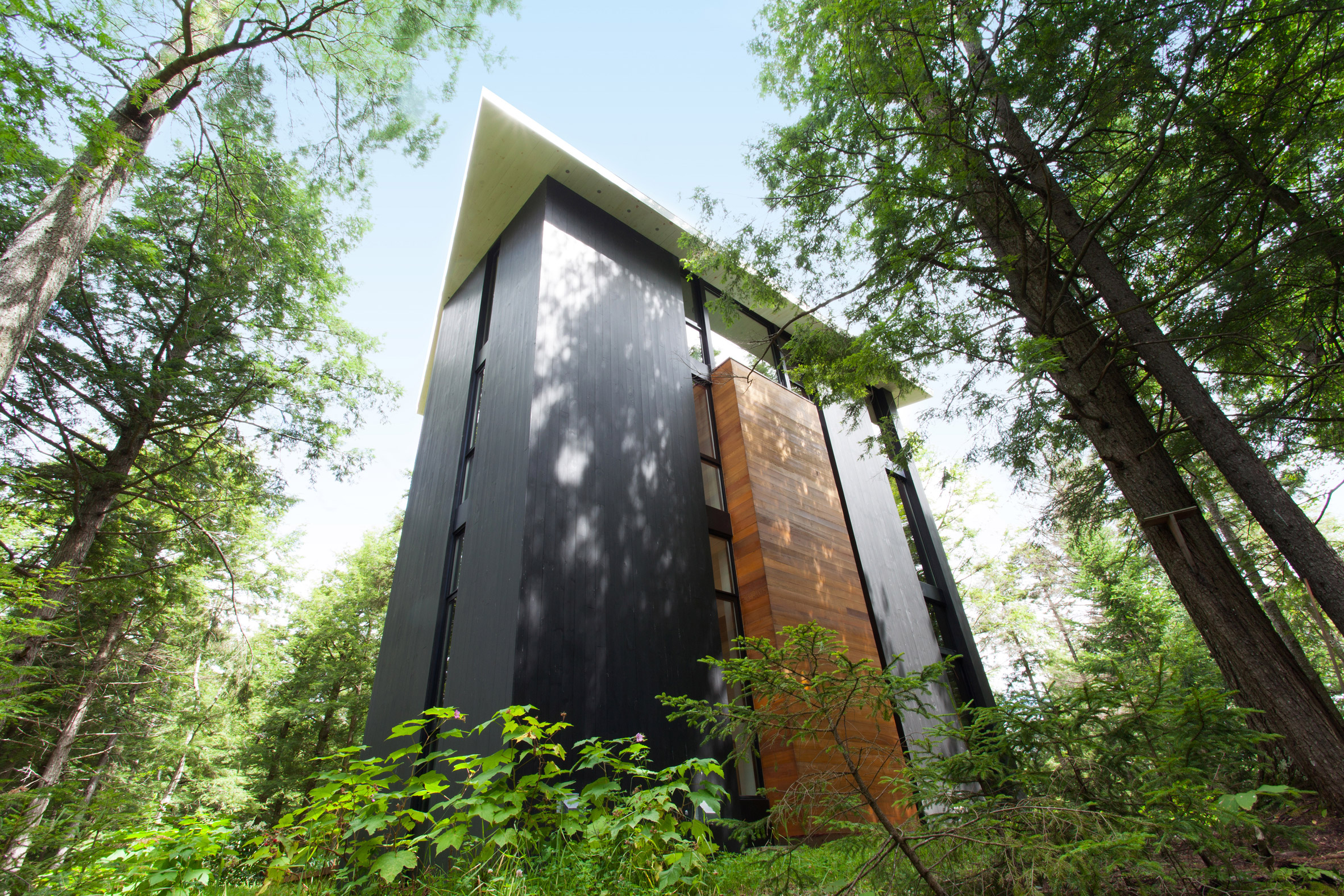 YH2 clads a Quebec holiday home for a sculptor in red cedar and blackened pine