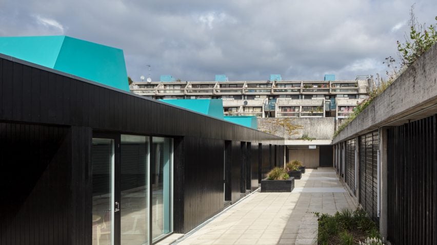 Black and electric blue structure surrounded by tiered concrete block of flats