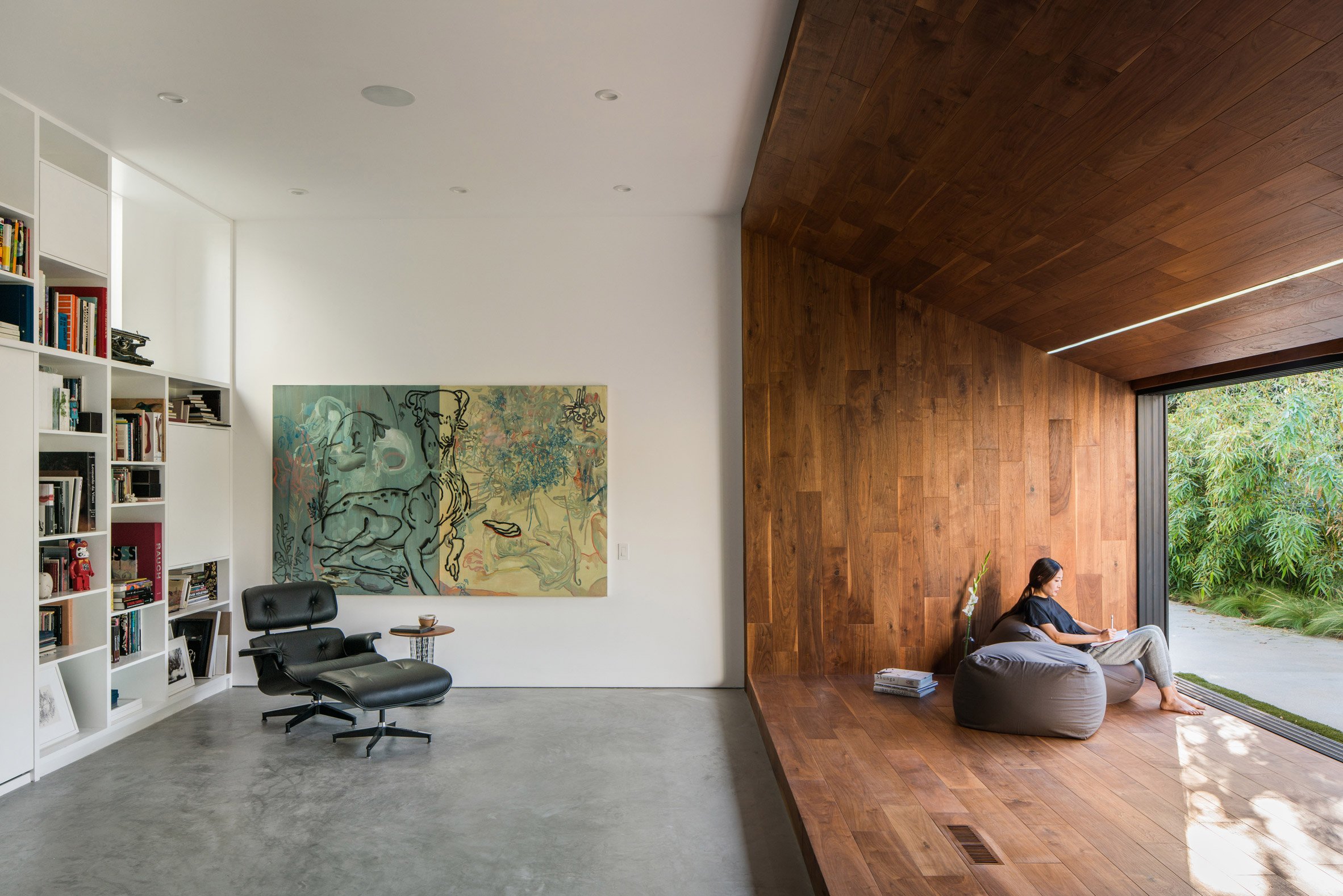 Walnut reading nook and white bookshelf in Frank Gehry house