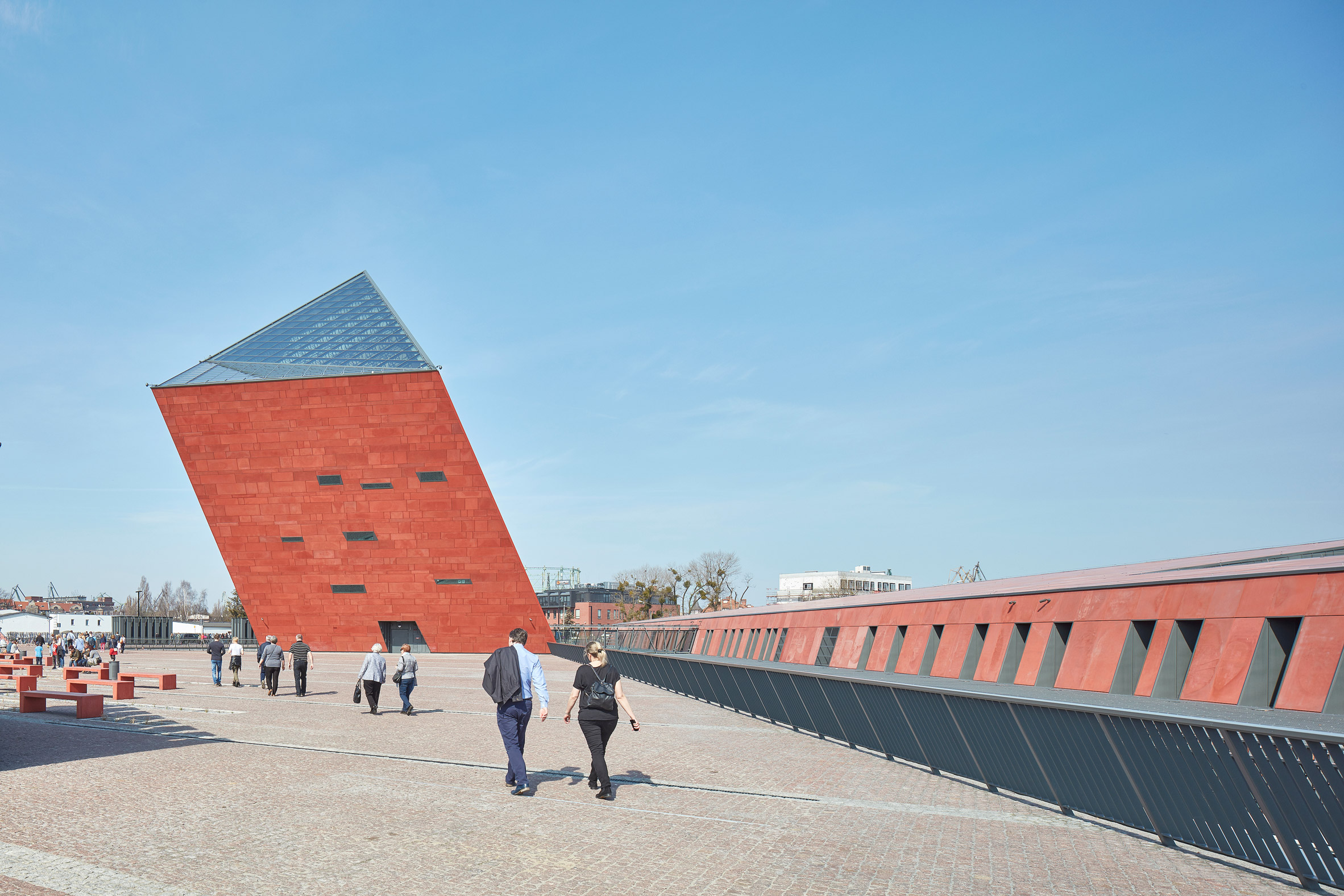 Tilted red tower marks entrance to Polish war museum by Kwadrat