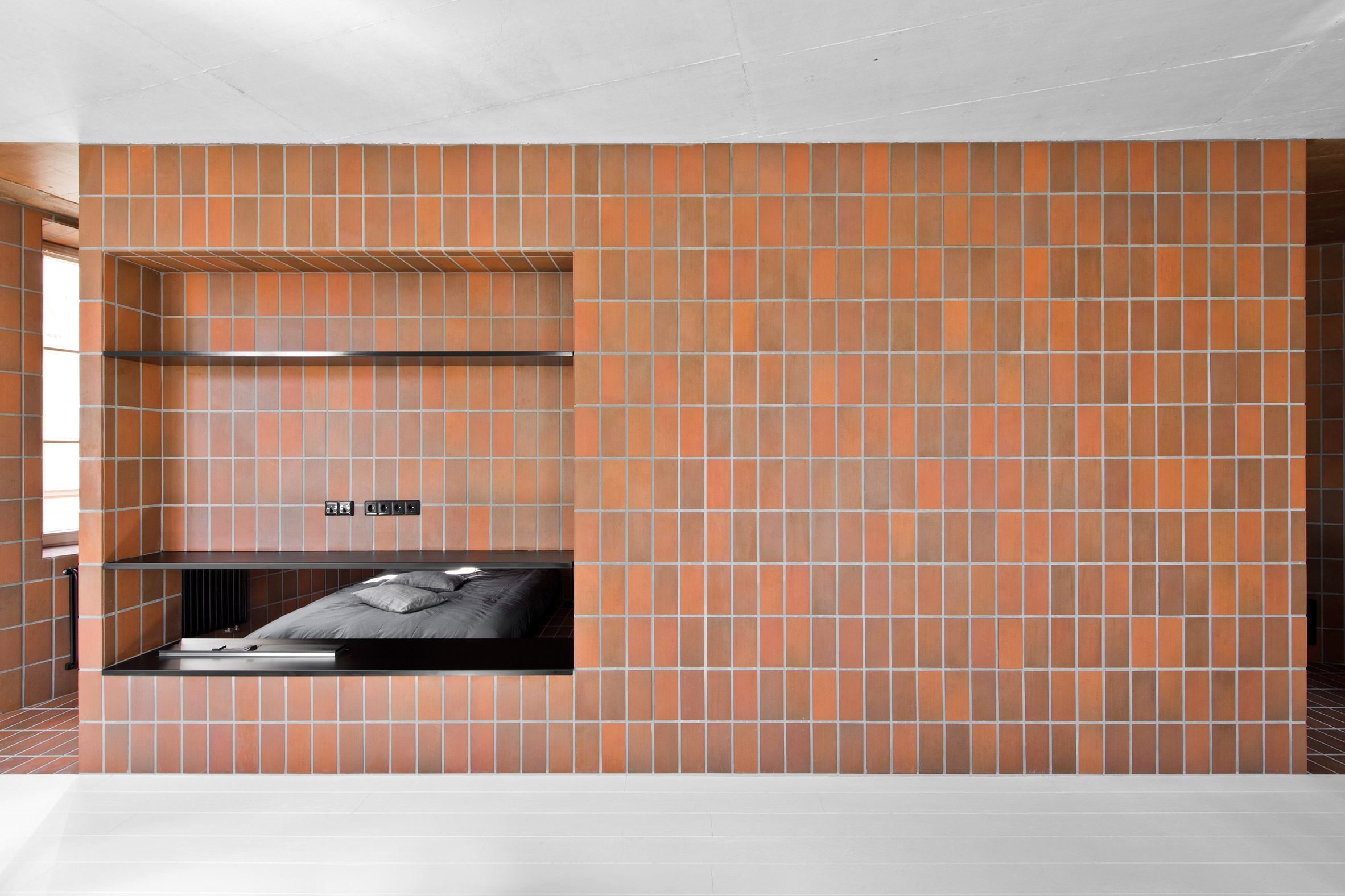 Terracotta-toned tiles divide Vilnius apartment into two contrasting halves