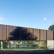 British firm Hawkins\Brown has completed a swimming-pool building at a school in Surrey, England, featuring an exposed timber frame that incorporates windows looking out onto the surrounding woodland.