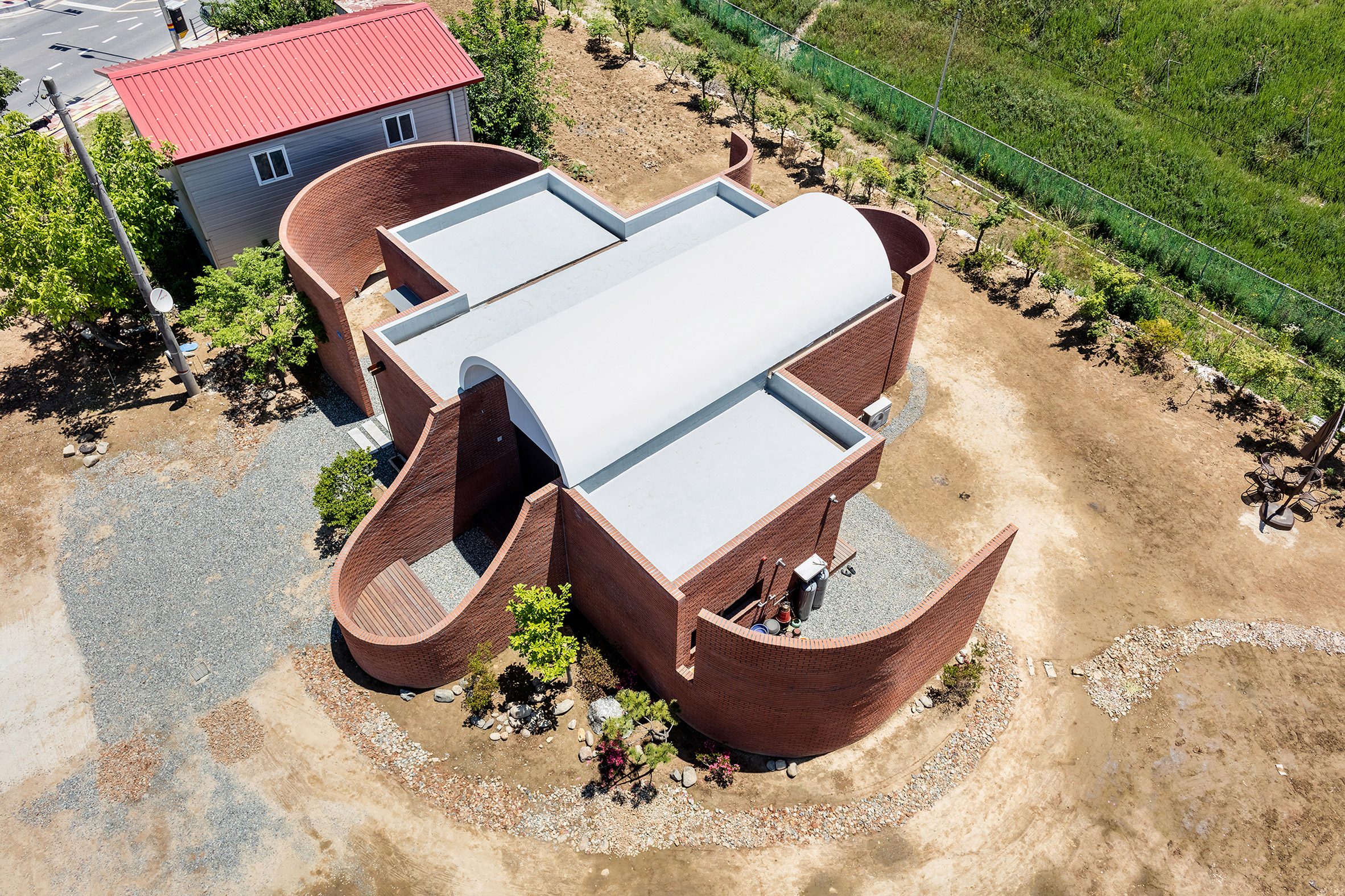 The Vault House by OBBA incorporates hidden gardens behind curving brick walls