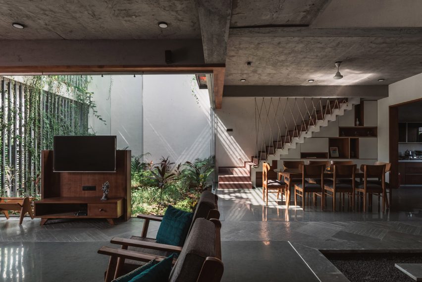 Living spaces at this house in the Indian city of Surat are arranged around a verdant courtyard lined with glass walls that can be retracted to open the interior up to the outdoors