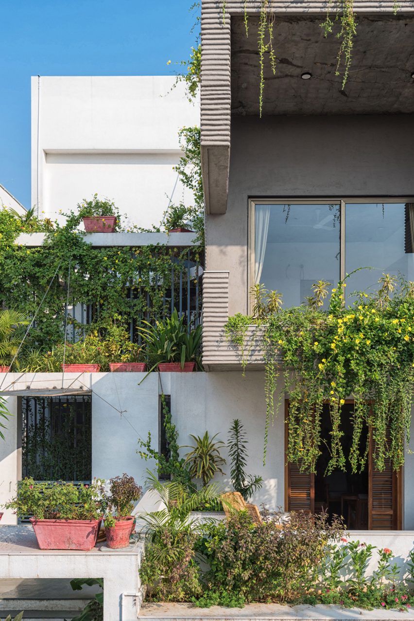 Living spaces at this house in the Indian city of Surat are arranged around a verdant courtyard lined with glass walls that can be retracted to open the interior up to the outdoors