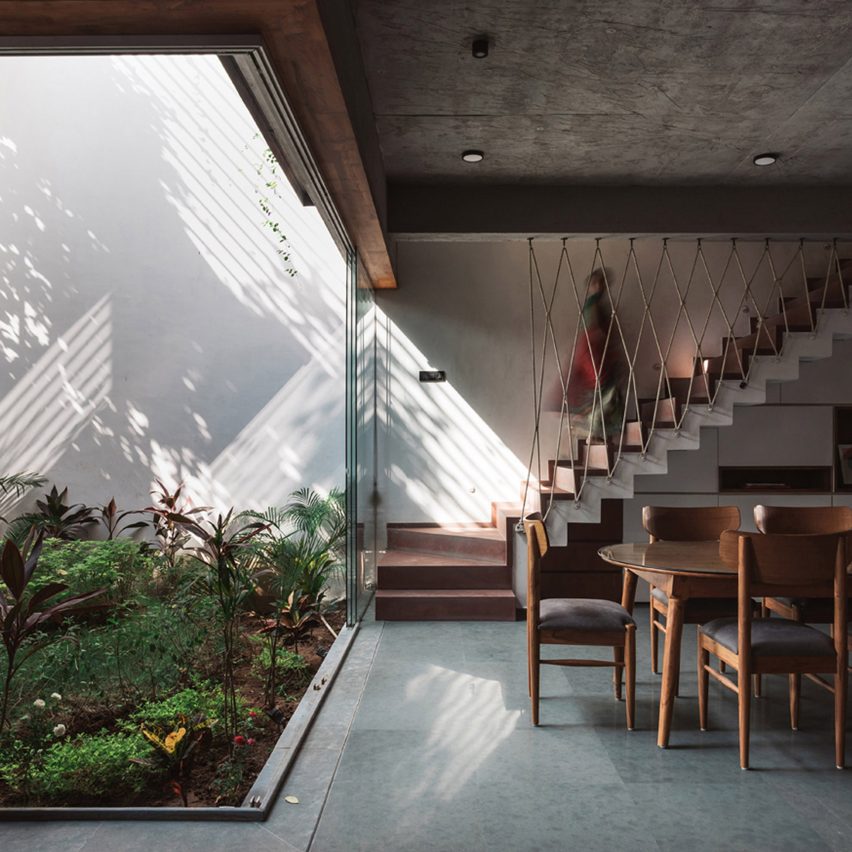 Living spaces at this house in the Indian city of Surat are arranged around a verdant courtyard lined with glass walls that can be retracted to open the interior up to the outdoors.