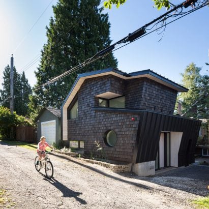 Pilotis support black house on Canadian hillside by Atelier General