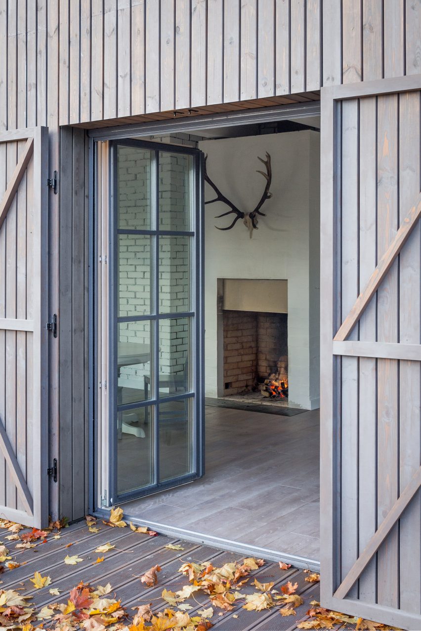 Aketuri Architektai conceals windows and doors behind large timber shutters at Lithuanian lakeside retreat
