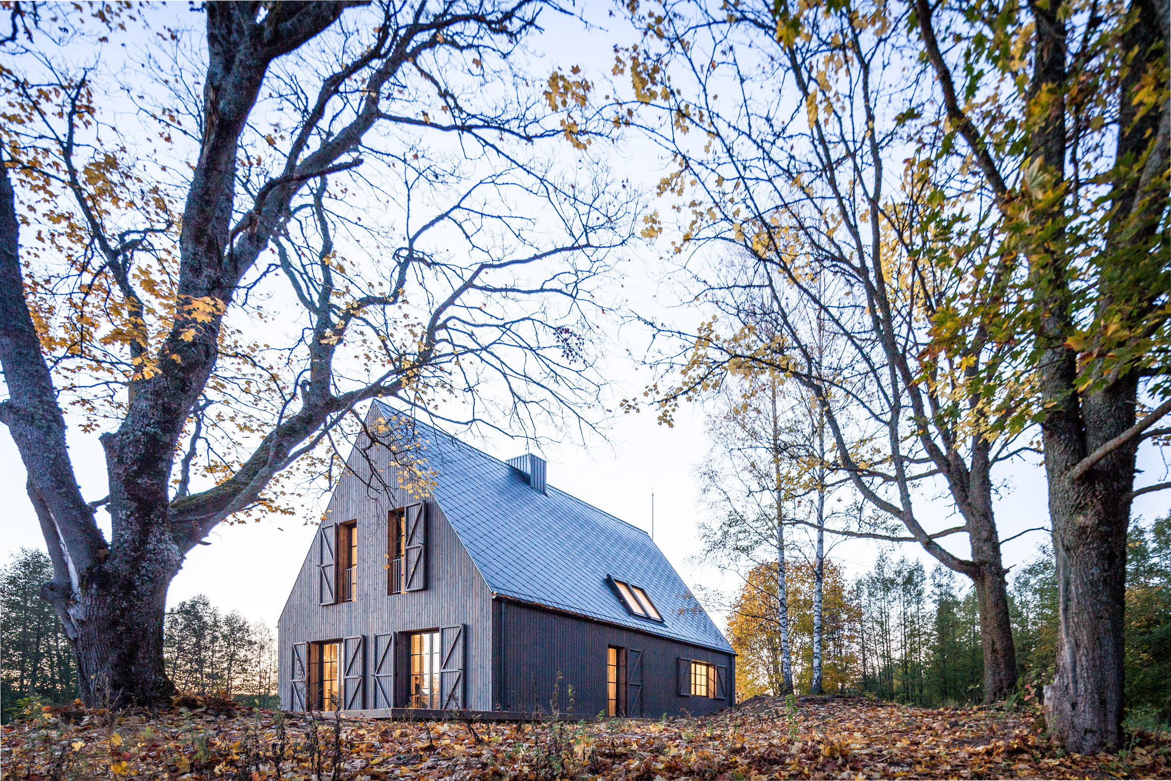 Aketuri Architektai conceals windows and doors behind large timber shutters at Lithuanian lakeside retreat