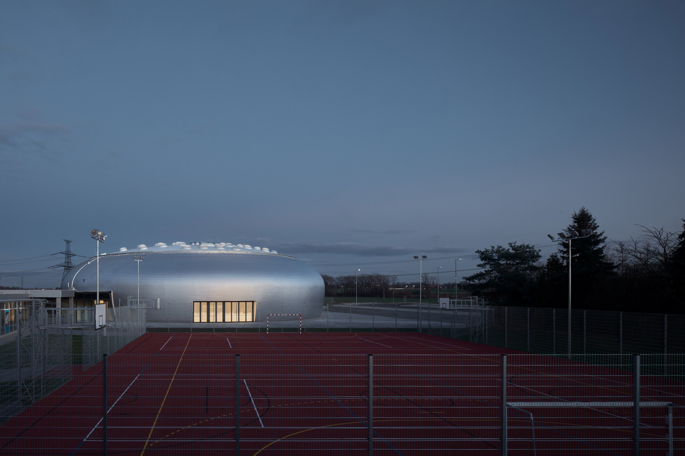 Domed sports hall by Sporadical is covered in scale-like aluminium shingles
