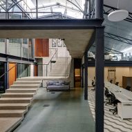 Offices in a converted warehouse centre around suspended concrete staircase
