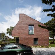 Villa IJsselzig by EVA Architecten is a riverside home featuring red-brick walls and a patinated copper roof