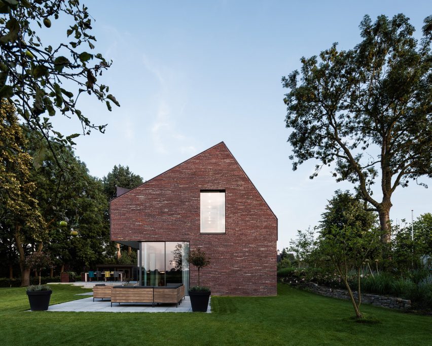 Villa IJsselzig by EVA Architecten is a riverside home featuring red-brick walls and a patinated copper roof