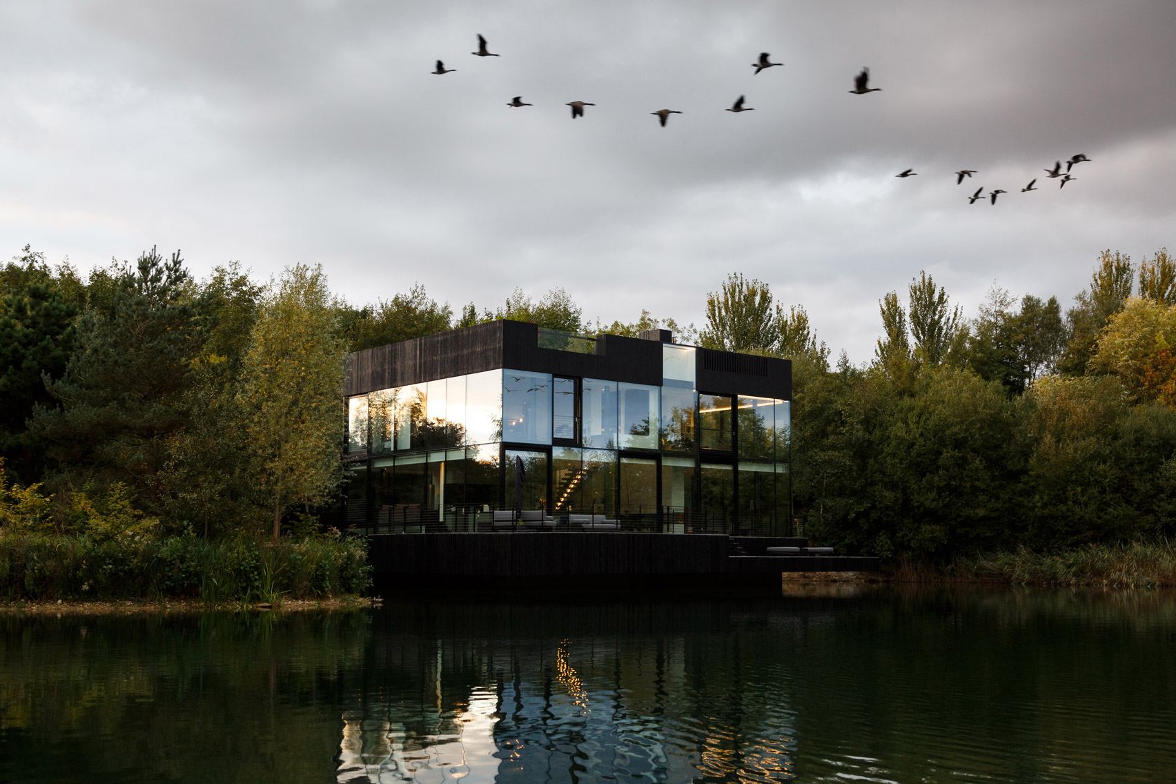 Mecanoo builds glass house partly submerged in a lake in the English countryside