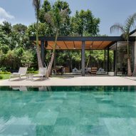 Sliding glass doors open on to a green stone pool in Israeli house