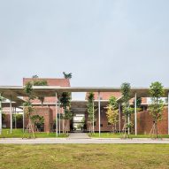 Elevated concrete pathway on stilts shades brick training centre in Hanoi