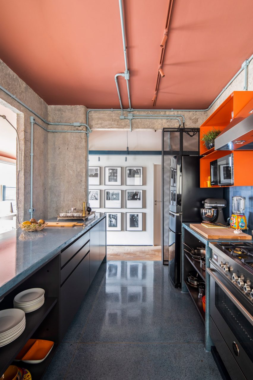 Kitchen with exposed services at the RF Apartment by SuperLimão with peach ceilings and concrete walls