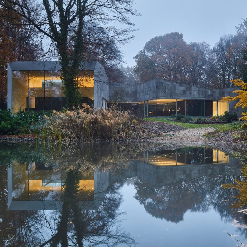 Forest house of stone and glass is reflected back in water
