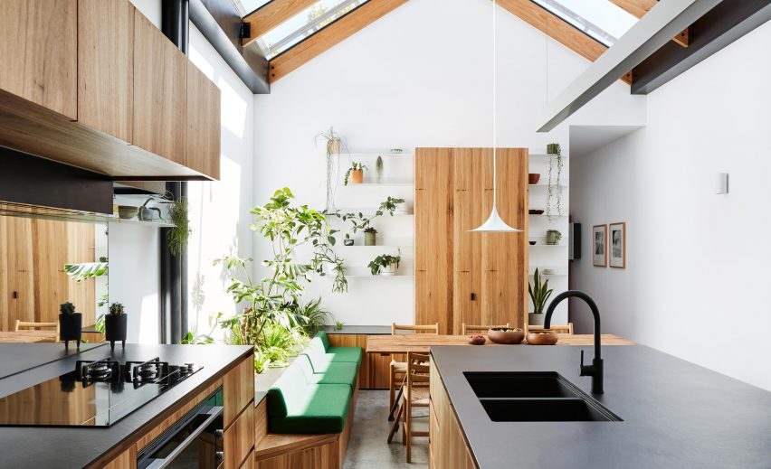A white kitchen with plants and wooden cabinetry