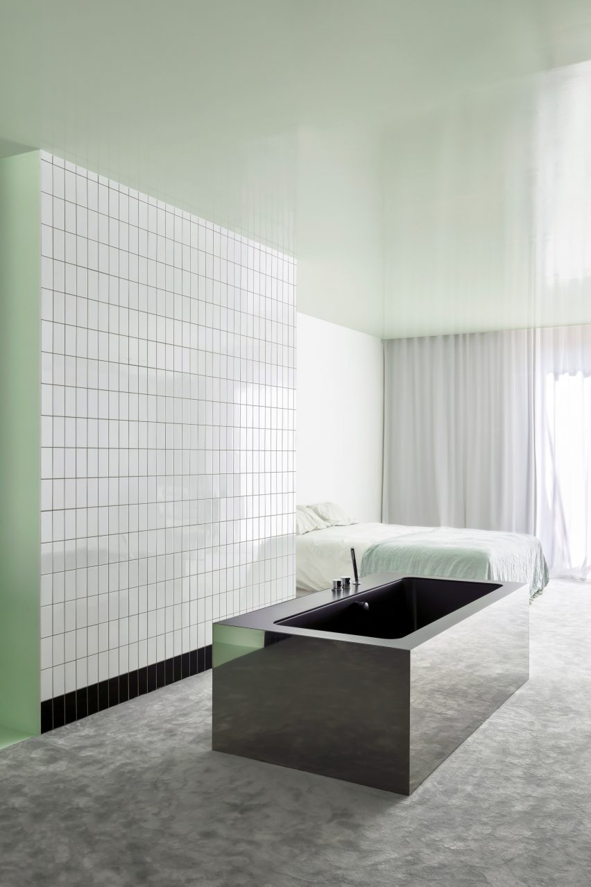 Apartment A by Atelier Dialect bedroom and adjoining open-plan private bathroom with rectangular bathtub