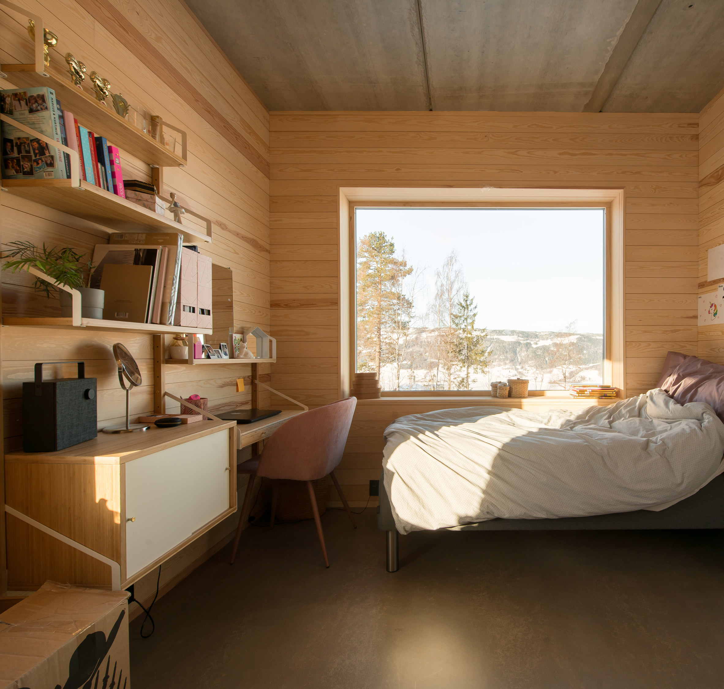 Bedroom with a desk in the red concrete house by Sanden+Hodnekvam