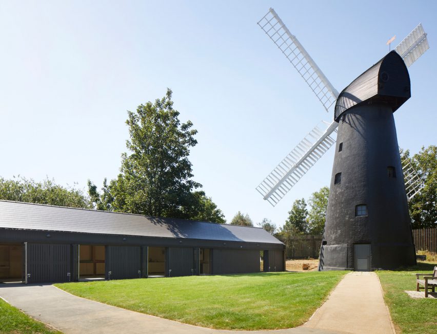 Black building next to black windmill with white sails