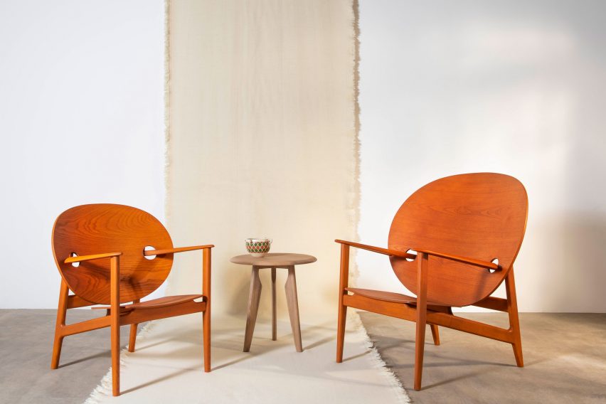 Two orange Iklwa armchairs chairs by benchmark next to a low wooden sidetable