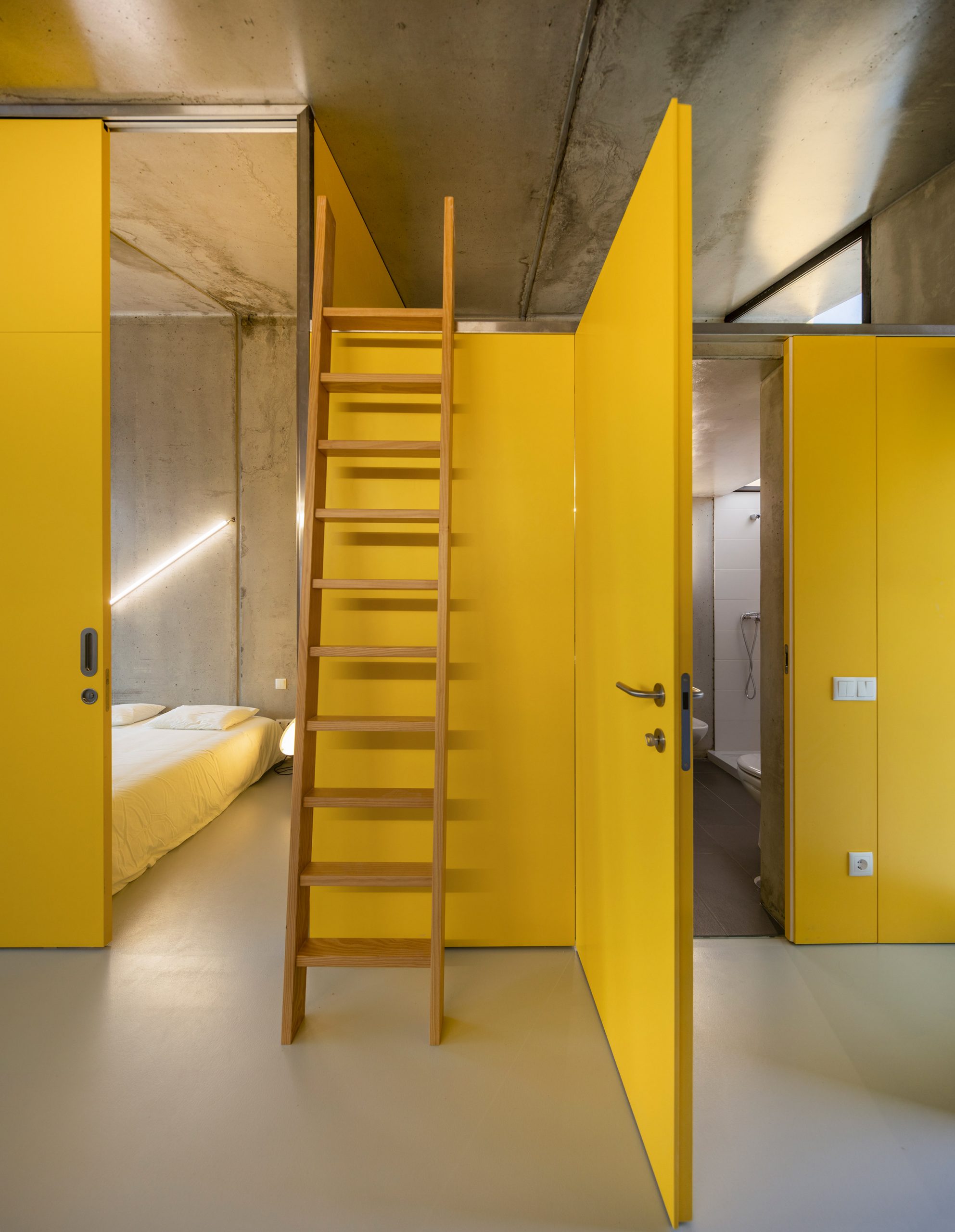 Yellow walls inside VDC modular prefabricated concrete housing by Summary in Portugal