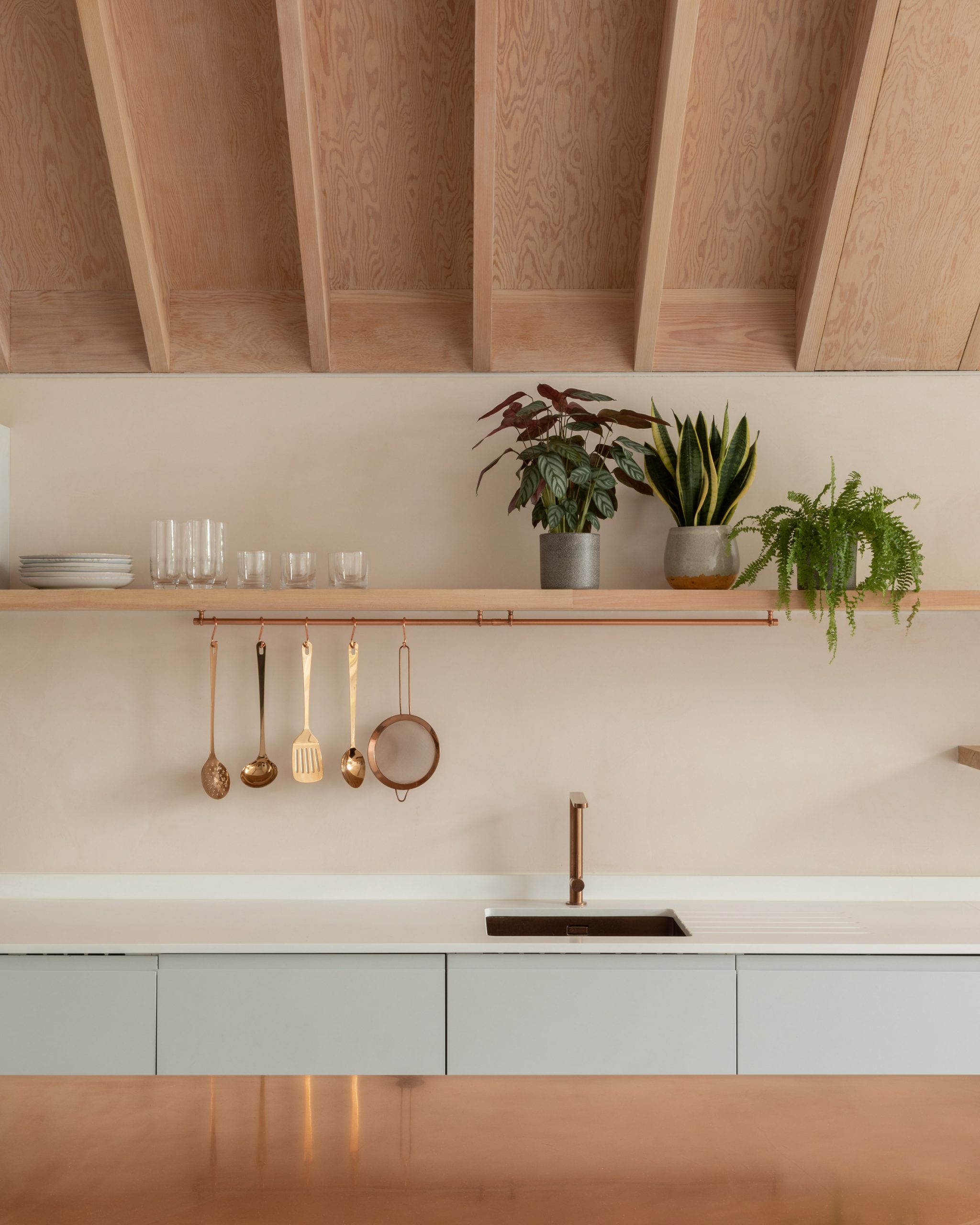 A pastel-hued kitchen with an exposed timber ceiling 