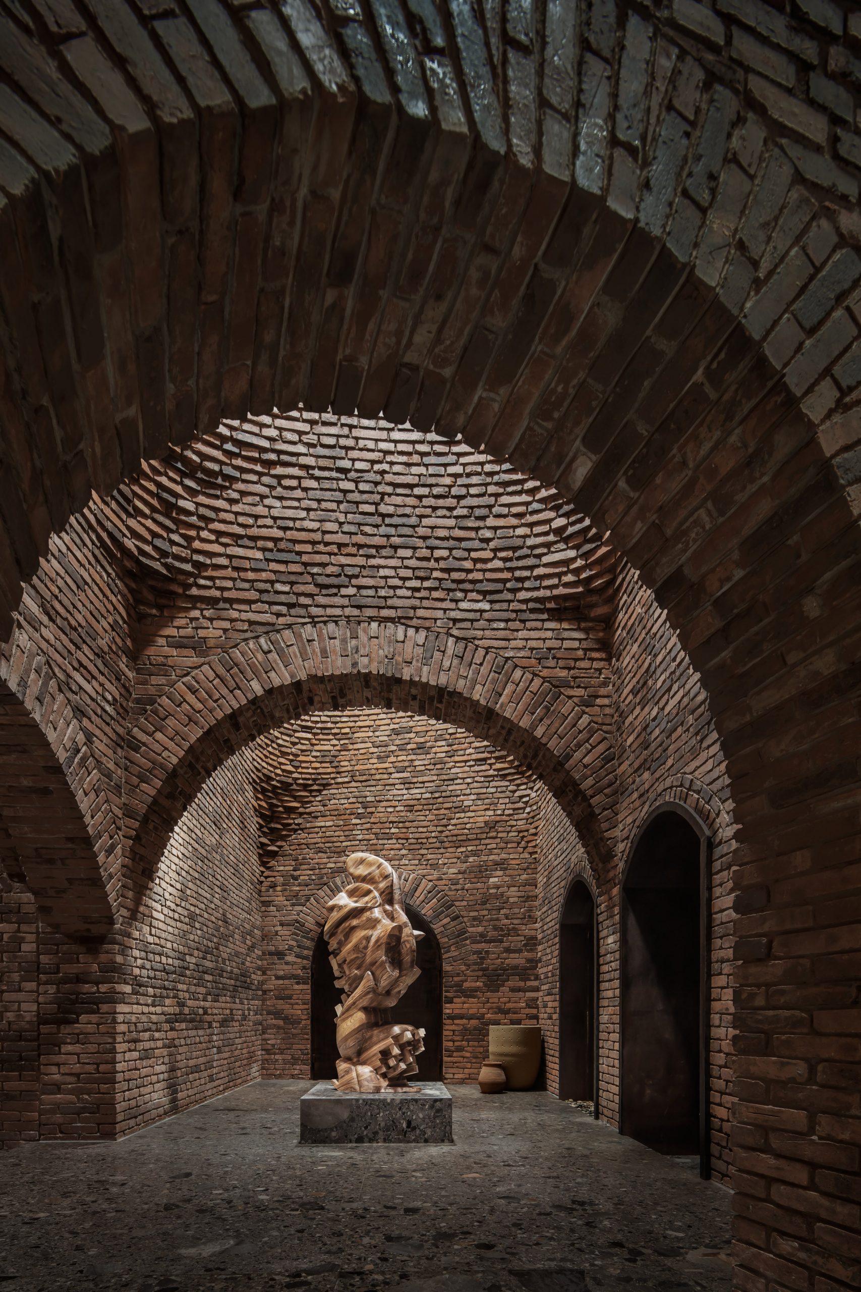 A sculpture within an arched-brick corridor