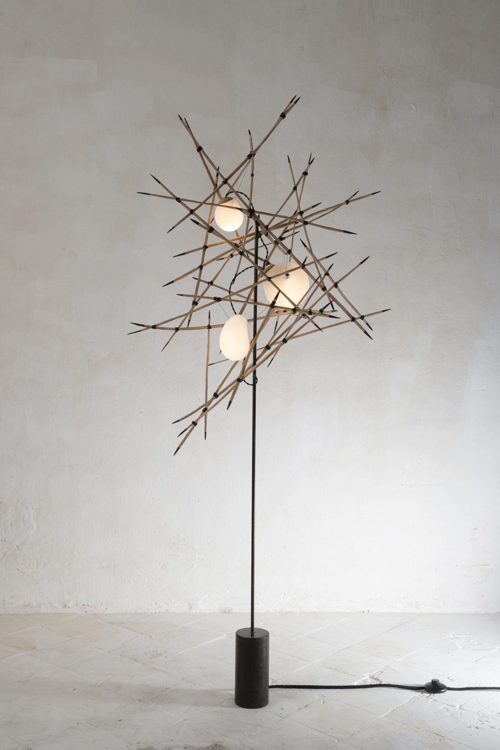 A floor lamp that looks like handfuls of matchsticks
