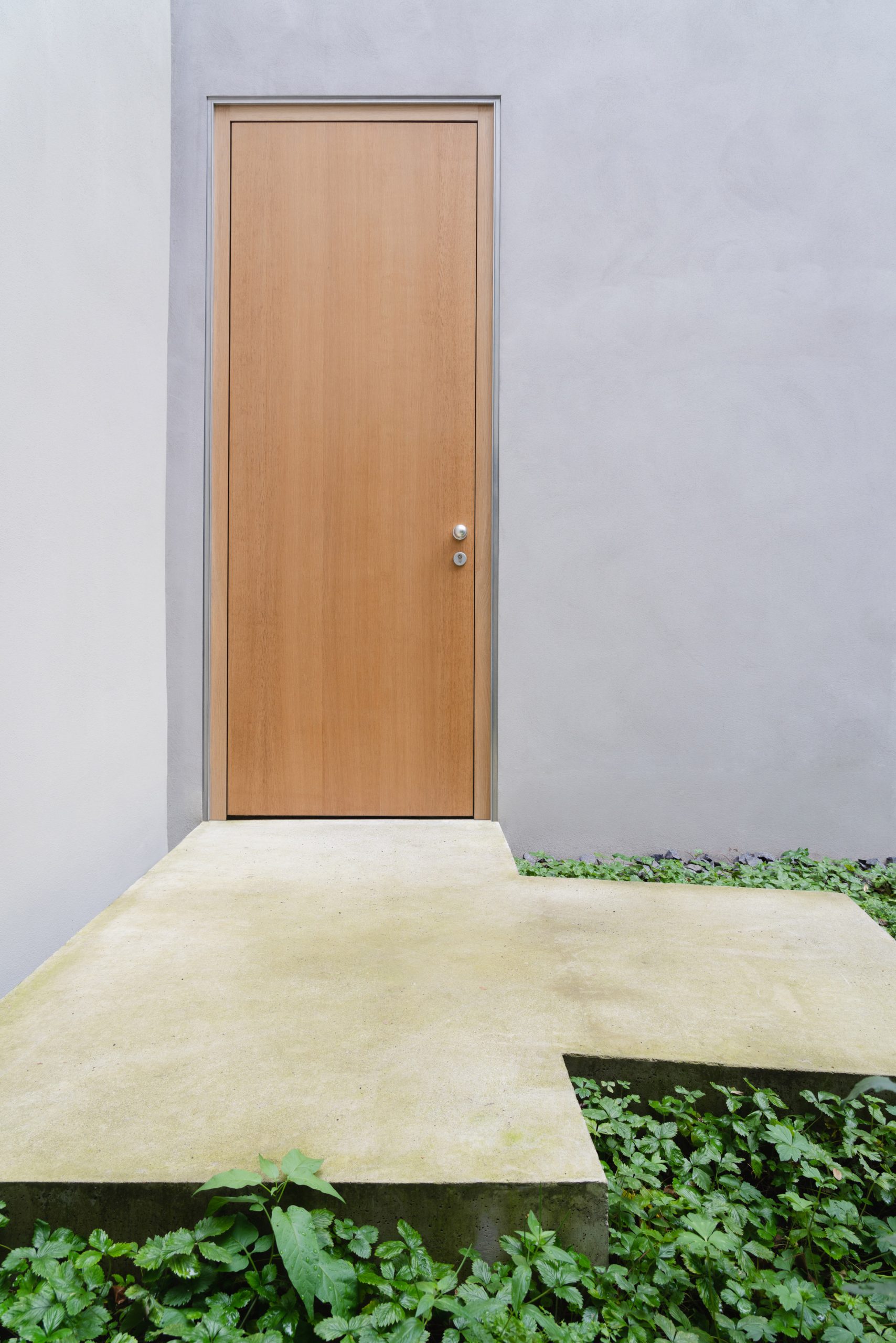 A wooden door is flush against the exterior walls by Batek Architekten