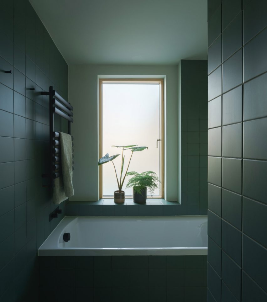 A bathroom lined with matt-green tiles in a terraced London house
