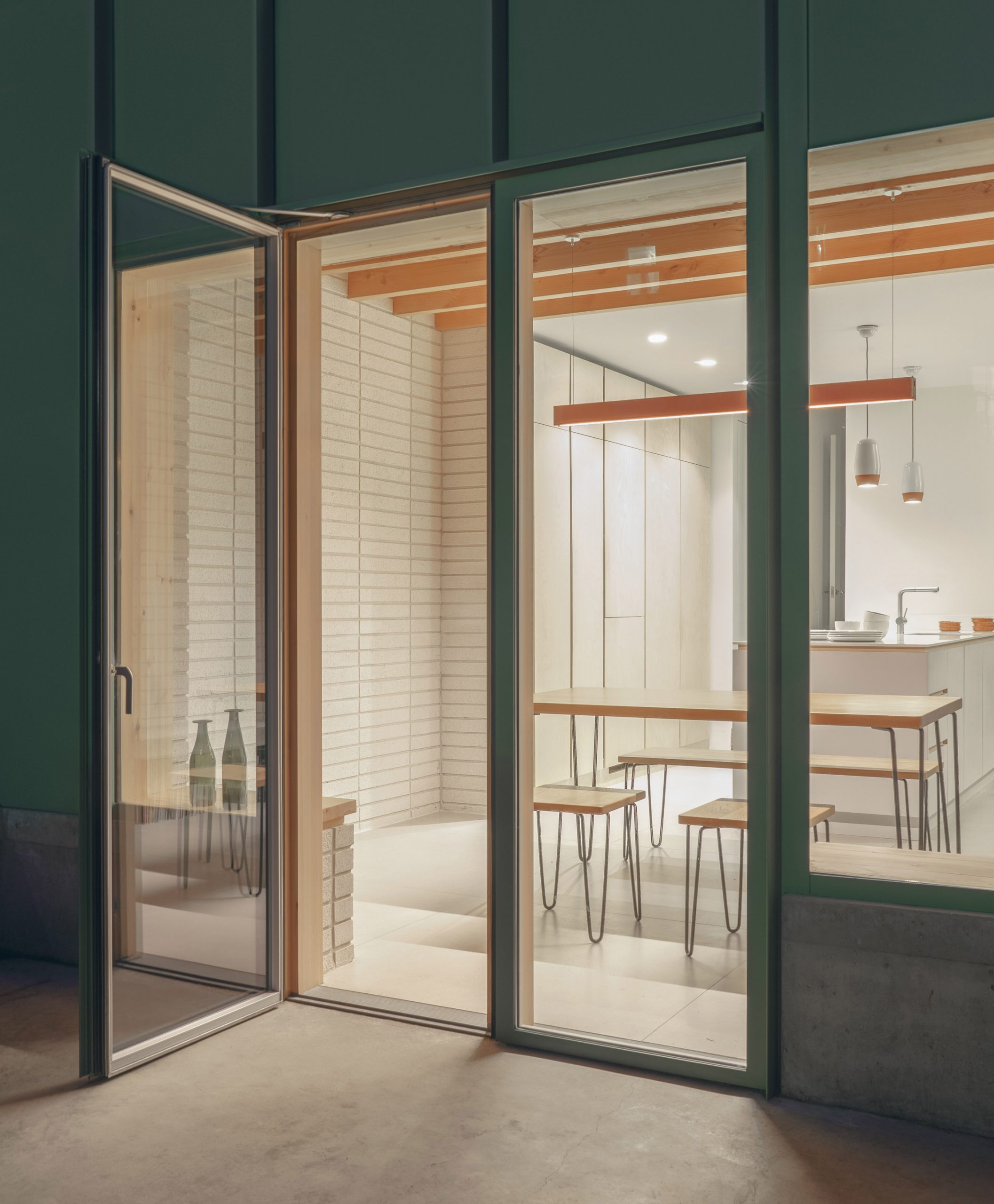 A kitchen inside a green aluminium-clad extension by DeDraft