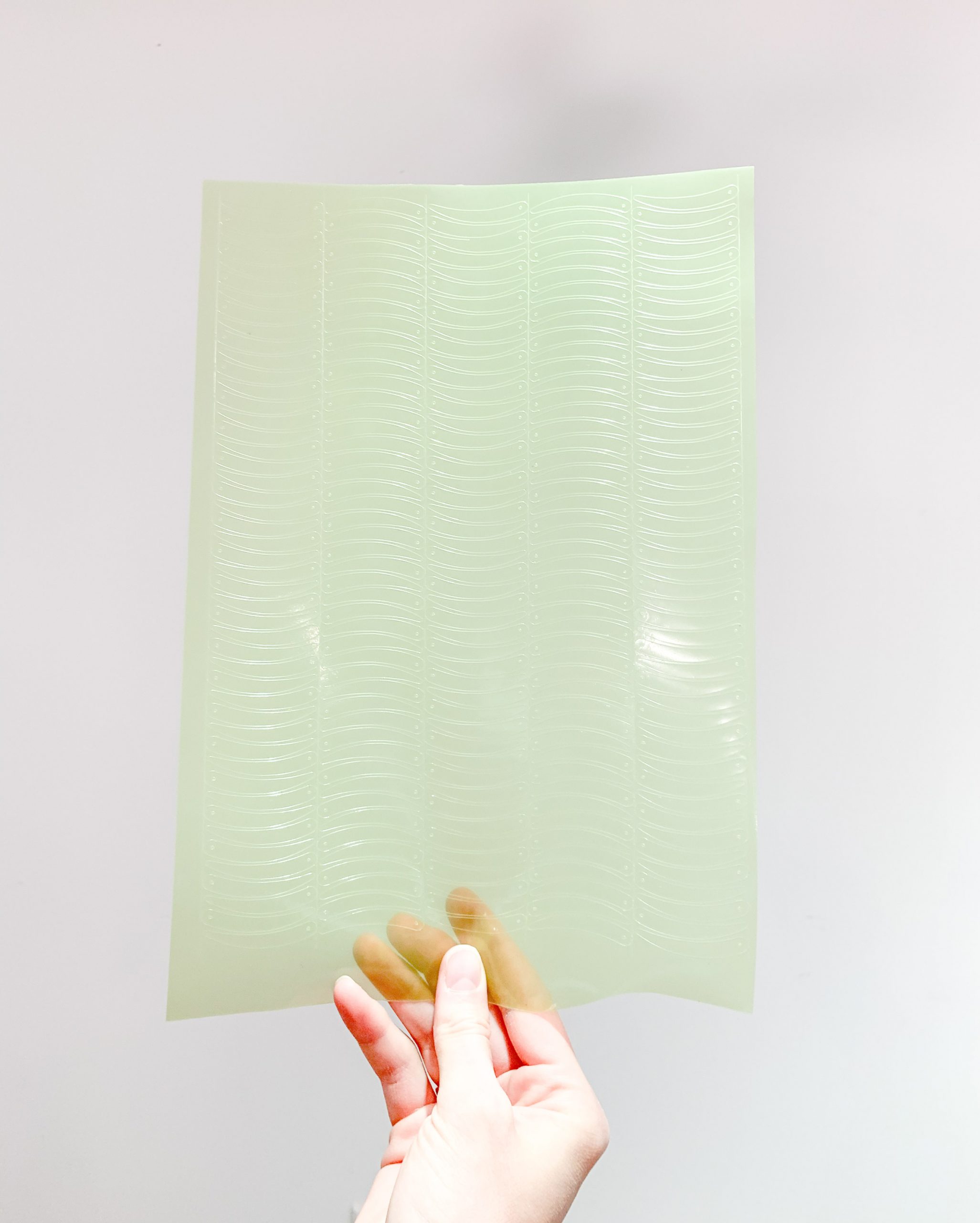 Hand holding a sheet of green bioplastic sequins