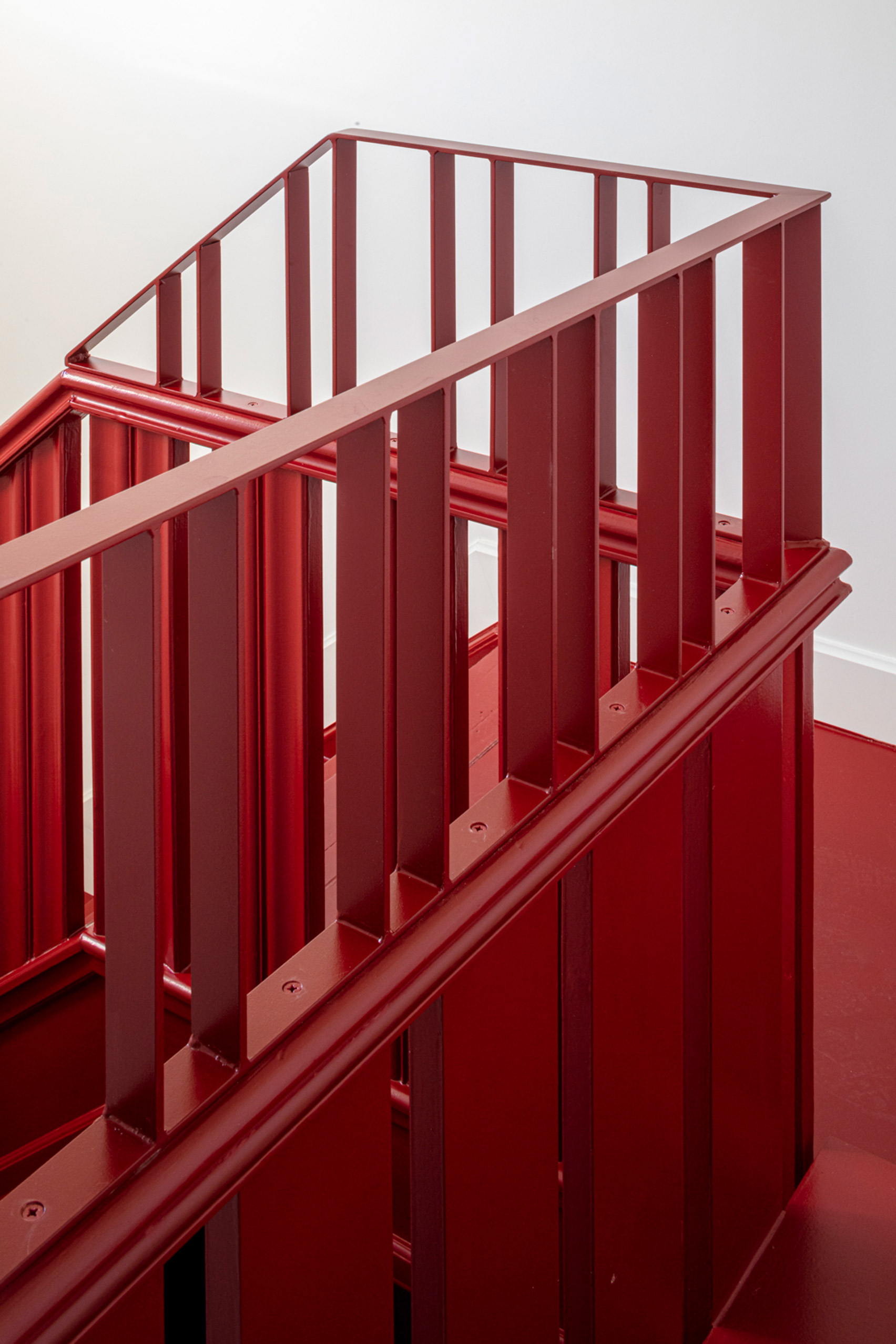 Red painted staircase with a steel and wooden balustrade